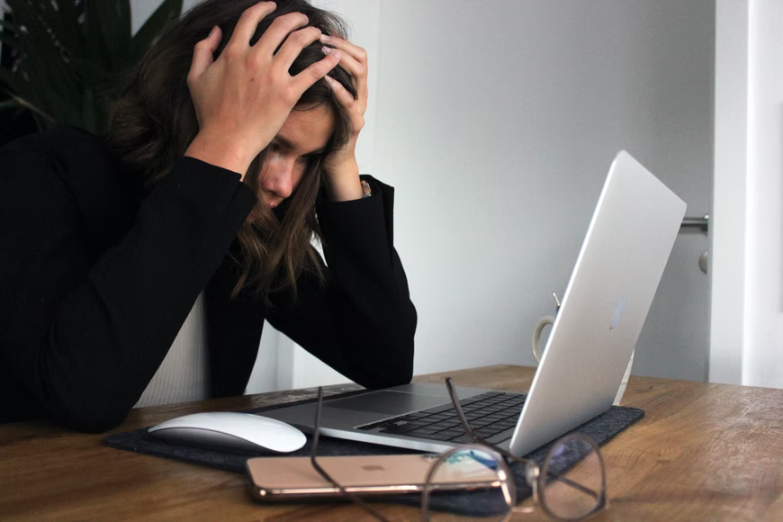 woman looking at computer with hands on her head