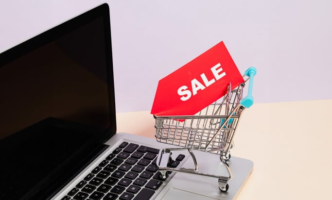 mini shopping cart with sale tag on laptop