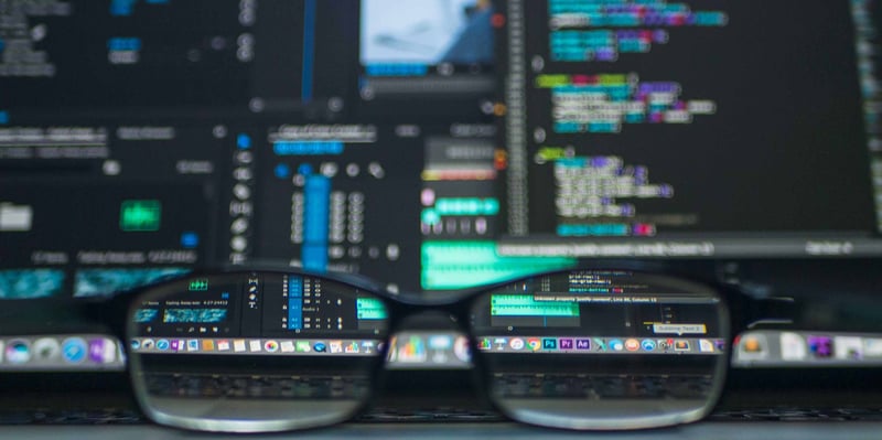 glasses in front of a computer showing code 